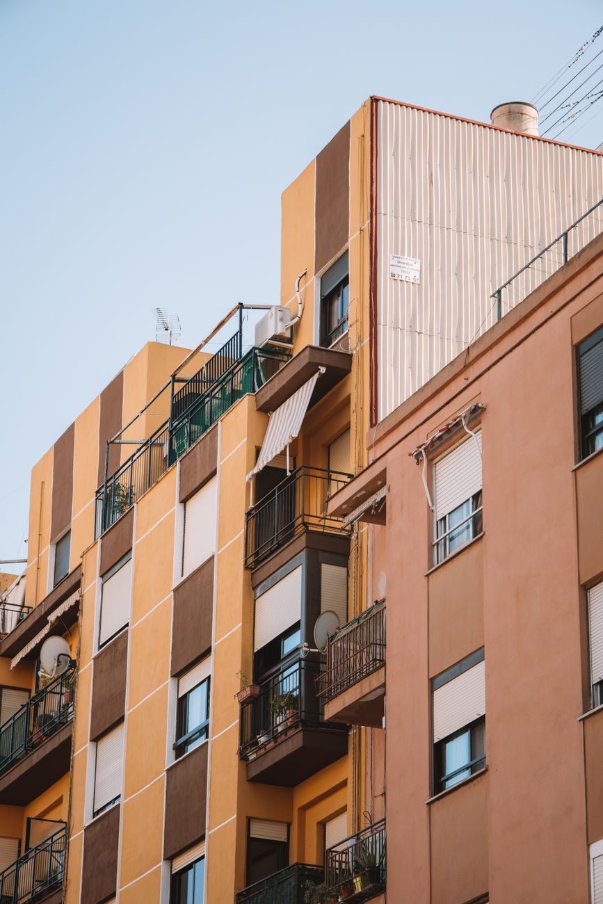 Fachada de un edificio de viviendas con balcones y ventanas de distintos tamaños.