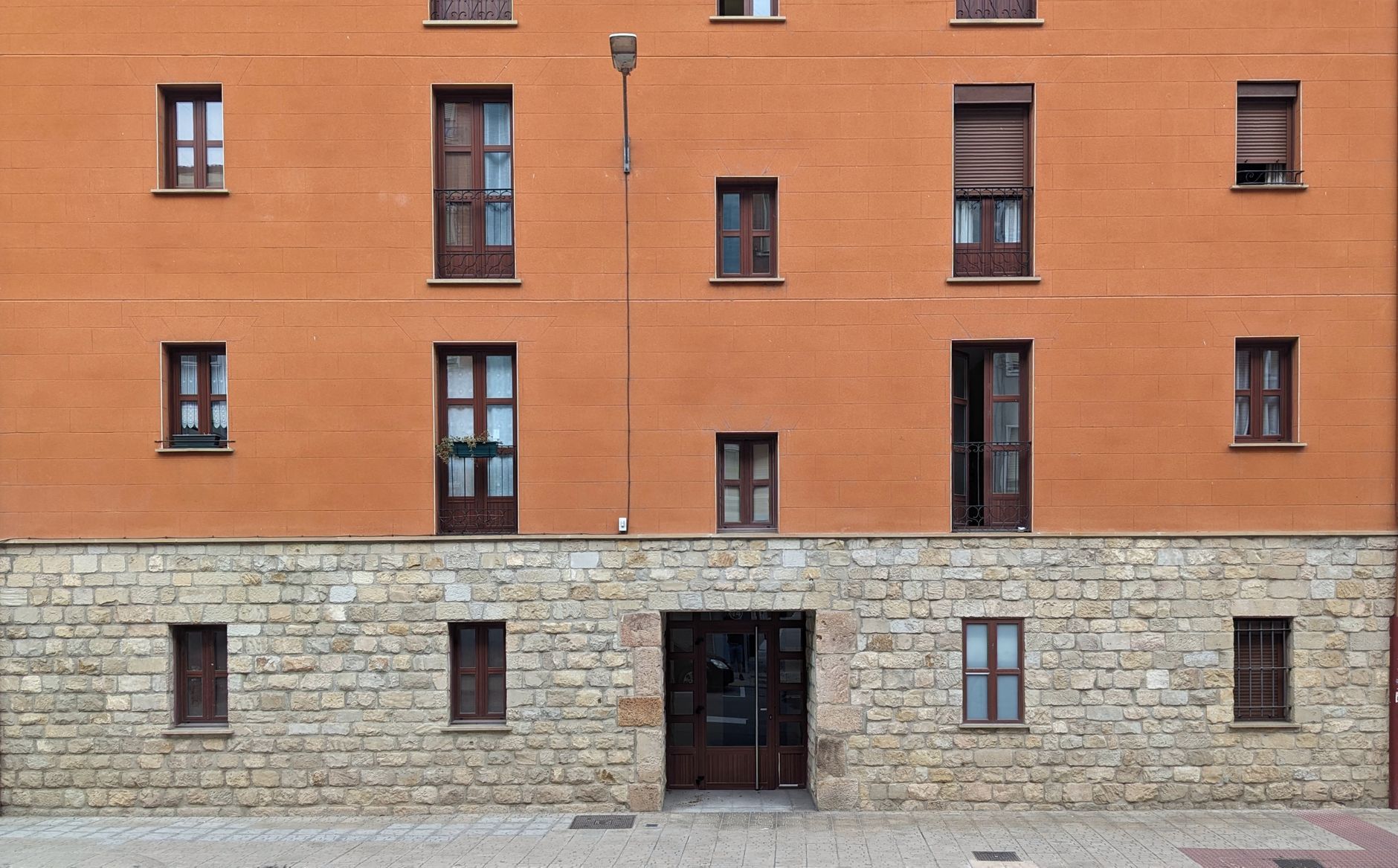 Bloque de viviendas moderno de fachada anaranjada con ventanas repetidas en altura.