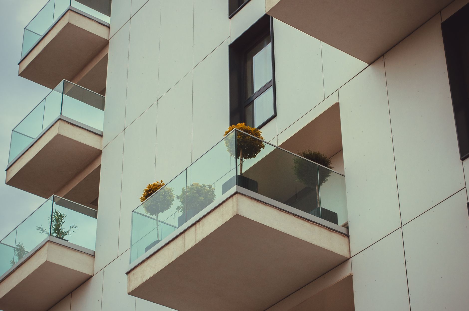Balcones acristalados de un edificio de viviendas reciente, con plantas en las terrazas.